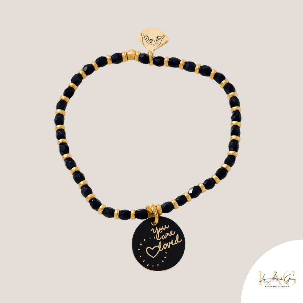 Gold and black beaded bracelet with a round black pendant engraved 'you are loved' in gold.