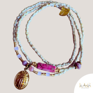 Three-strand beaded wrap bracelet with pale blue cube beads, gold spacers, a pink magenta focal bead, and a gold oval pendant hanging from the strands.