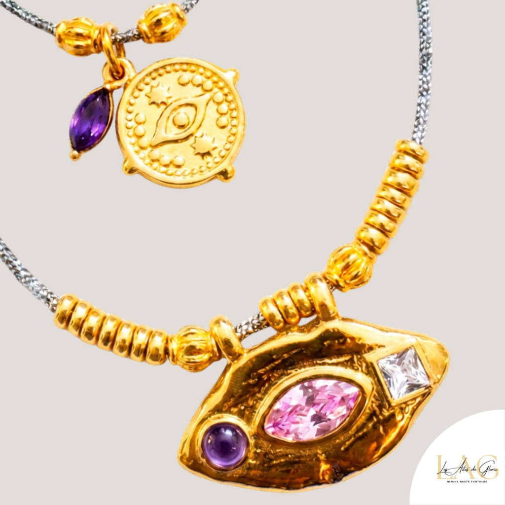Gold-toned pendant necklace featuring a pink marquise gem, purple cabochon, and a small square white stone on a textured chain.